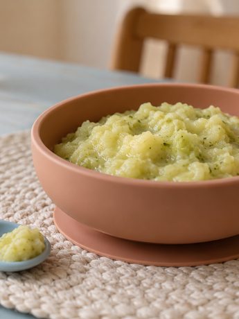 Kelkáposzta-főzelék terrakotta babatálkában, kék faasztalon, fa nyelű etetőkanállal.