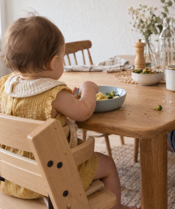 Baba és felnőtt közös, nyugodt étkezése világos otthoni környezetben.