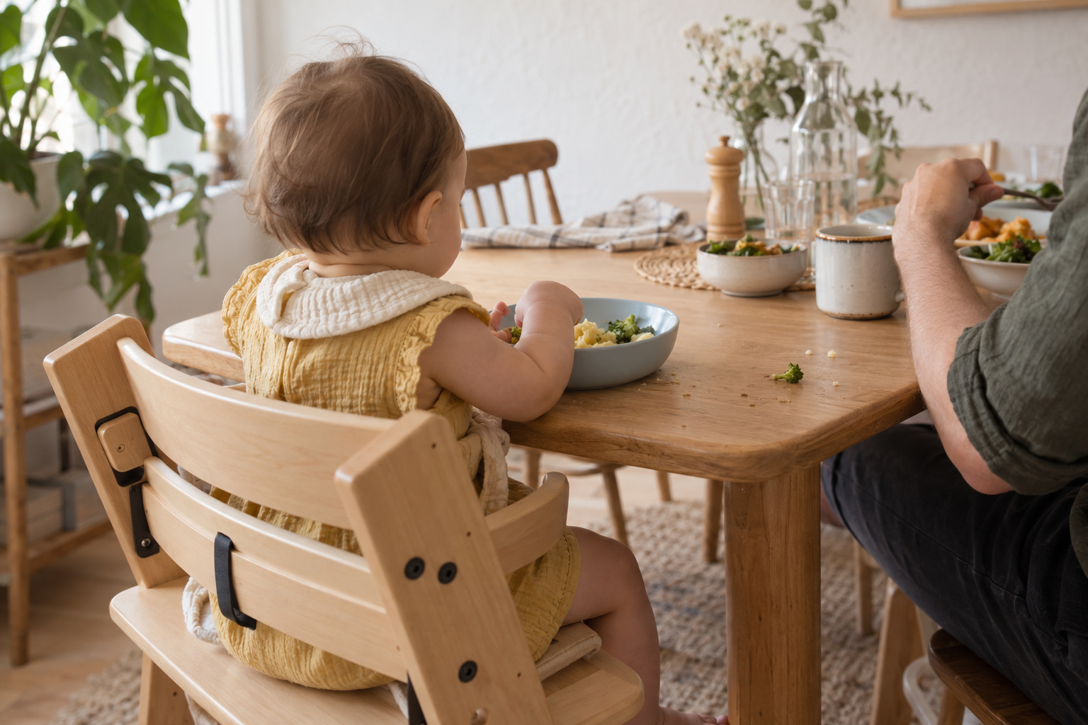 Baba és felnőtt közös, nyugodt étkezése világos otthoni környezetben.